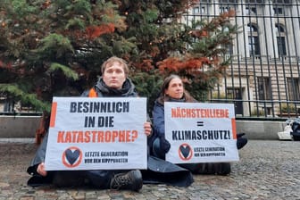 Zwei Aktivisten der "Letzten Generation" sitzen vor einem Weihnachtsbaum in Berlin. Auch in Bayern waren sie aktiv.