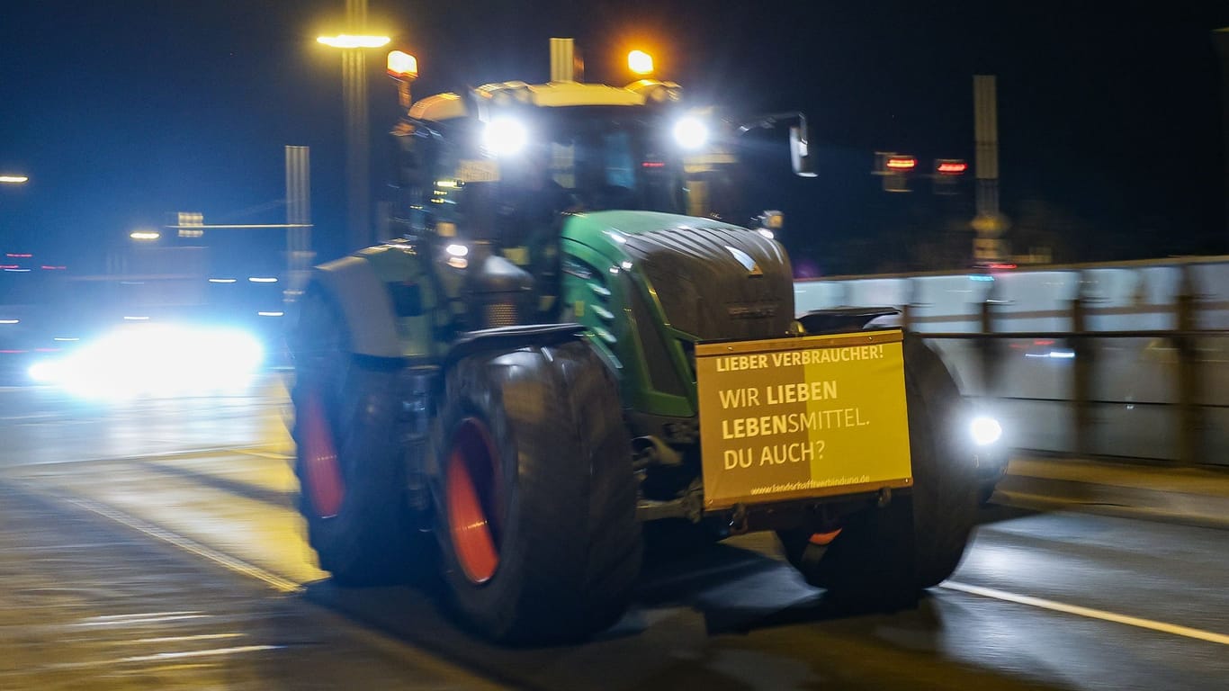 Leipzig: Ein Landwirt fährt mit seinem Traktor und einem Protestplakat am frühen Morgen durch den beginnenden Berufsverkehr.