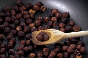 Haselnüsse rösten: Die Nüsse in einer beschichteten Pfanne ohne Öl scharf anrösten, bis die Haut schwarz wird und abplatzt.