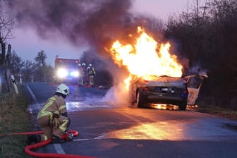 Feuerwehrleute bei der Löschung des Brandautos in Freital: Die beiden Insassen kamen in ein Krankenhaus.