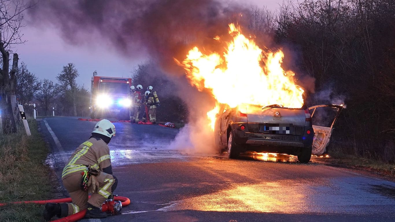 Feuerwehrleute bei der Löschung des Brandautos in Freital: Die beiden Insassen kamen in ein Krankenhaus.
