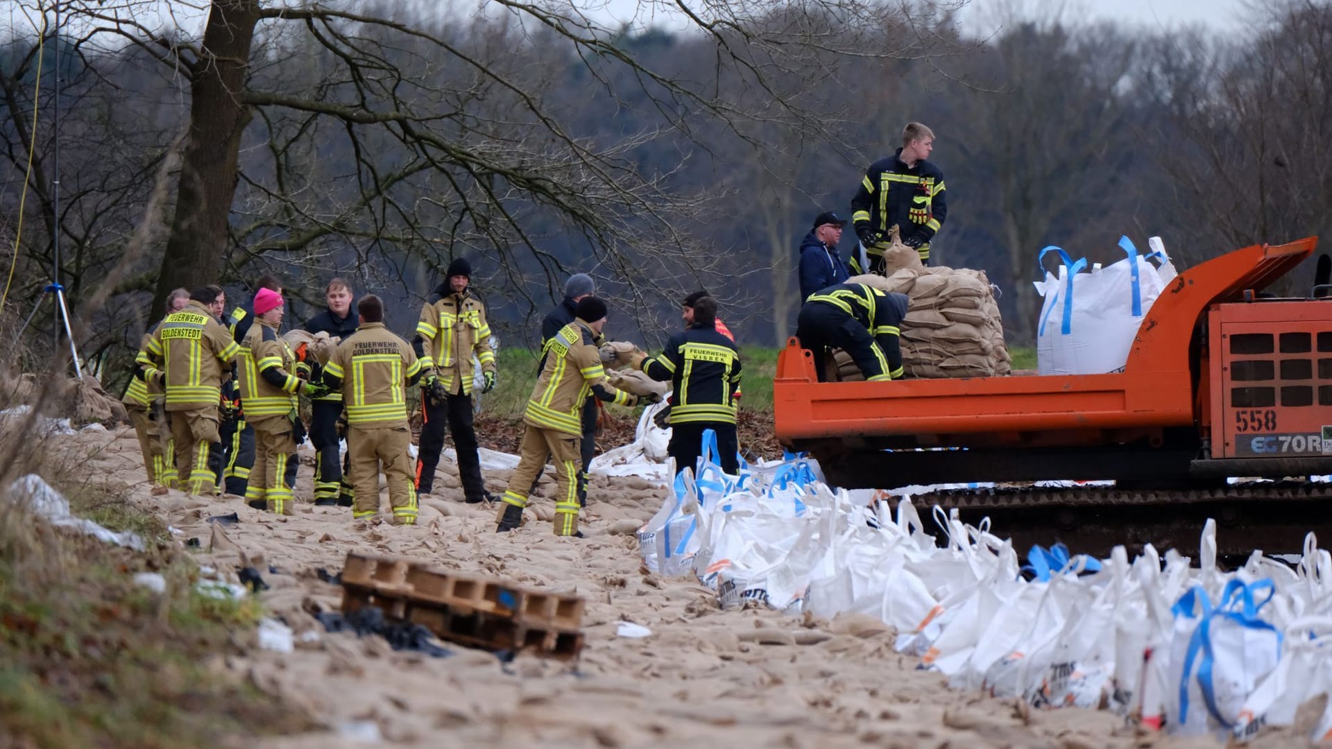 Feuerwehrleute sichern einen Deich bei Sandkrug.