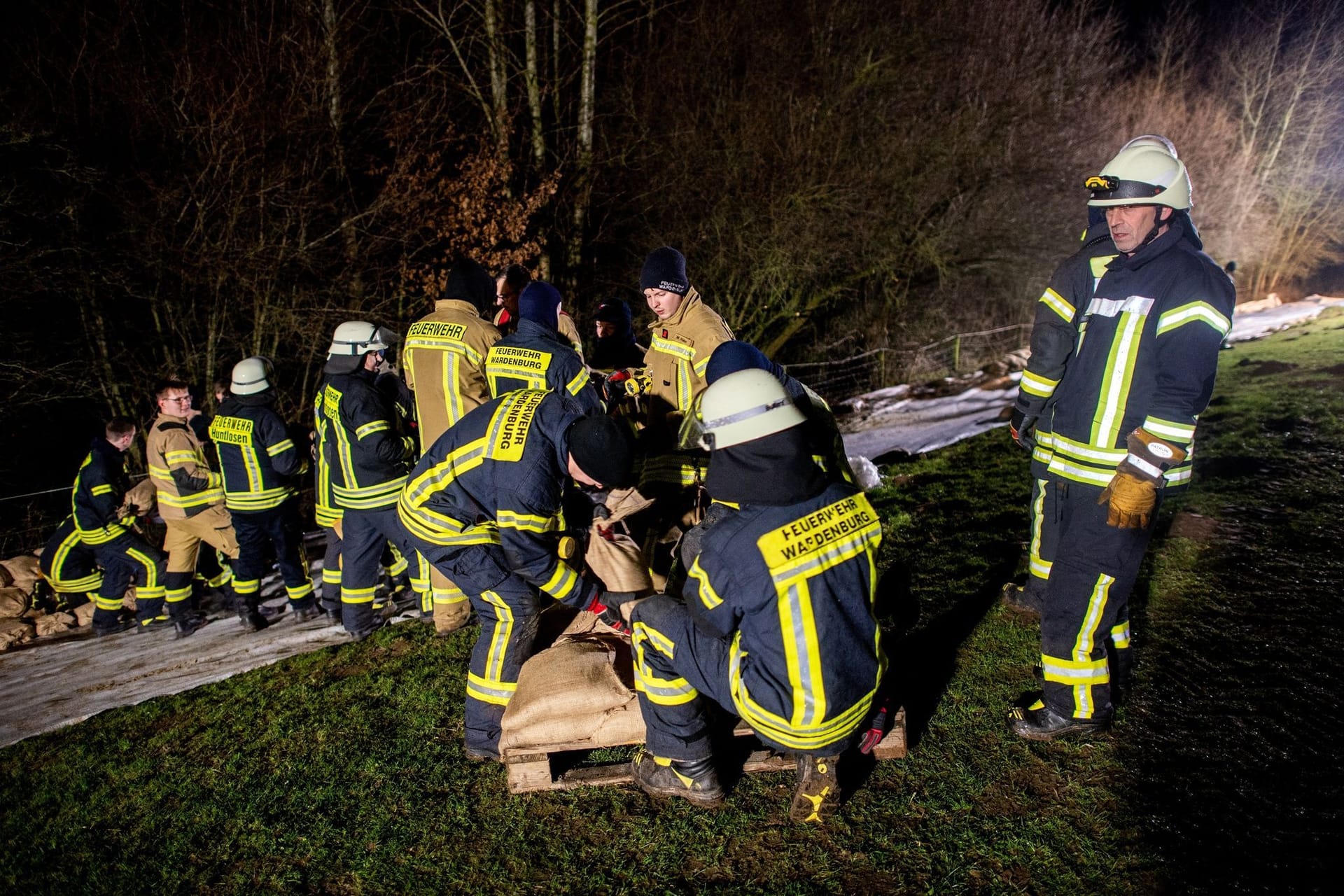 Einsatzkräfte der Feuerwehr sichern den aufgeweichten Deich der Hunte nahe der Ortschaft Astrup mit Vlies und Sandsäcken.
