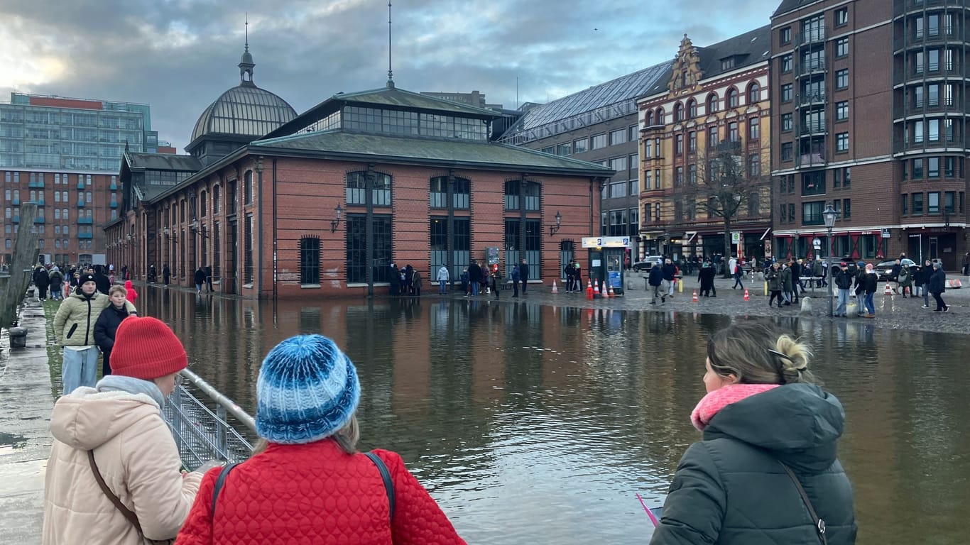 Zahlreiche Passanten und Spaziergänger sehen sich den leicht unter Wasser stehenden Fischmarkt an. Die Hochwasserlage in Hamburg ist am ersten Weihnachtstag weitgehend entspannt geblieben.