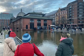Zahlreiche Passanten und Spaziergänger sehen sich den leicht unter Wasser stehenden Fischmarkt an. Die Hochwasserlage in Hamburg ist am ersten Weihnachtstag weitgehend entspannt geblieben.