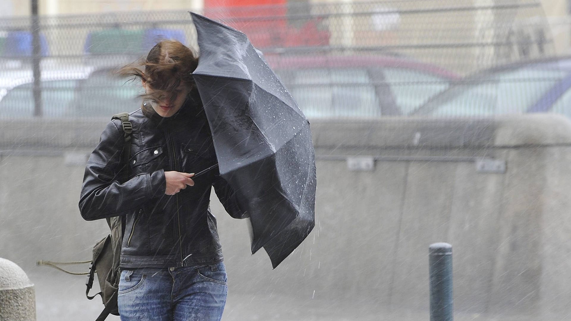 Junge Frau mit Regenschirm im Sturm (Symbolbild): In Hamburg wird das Wetter ungemütlich.