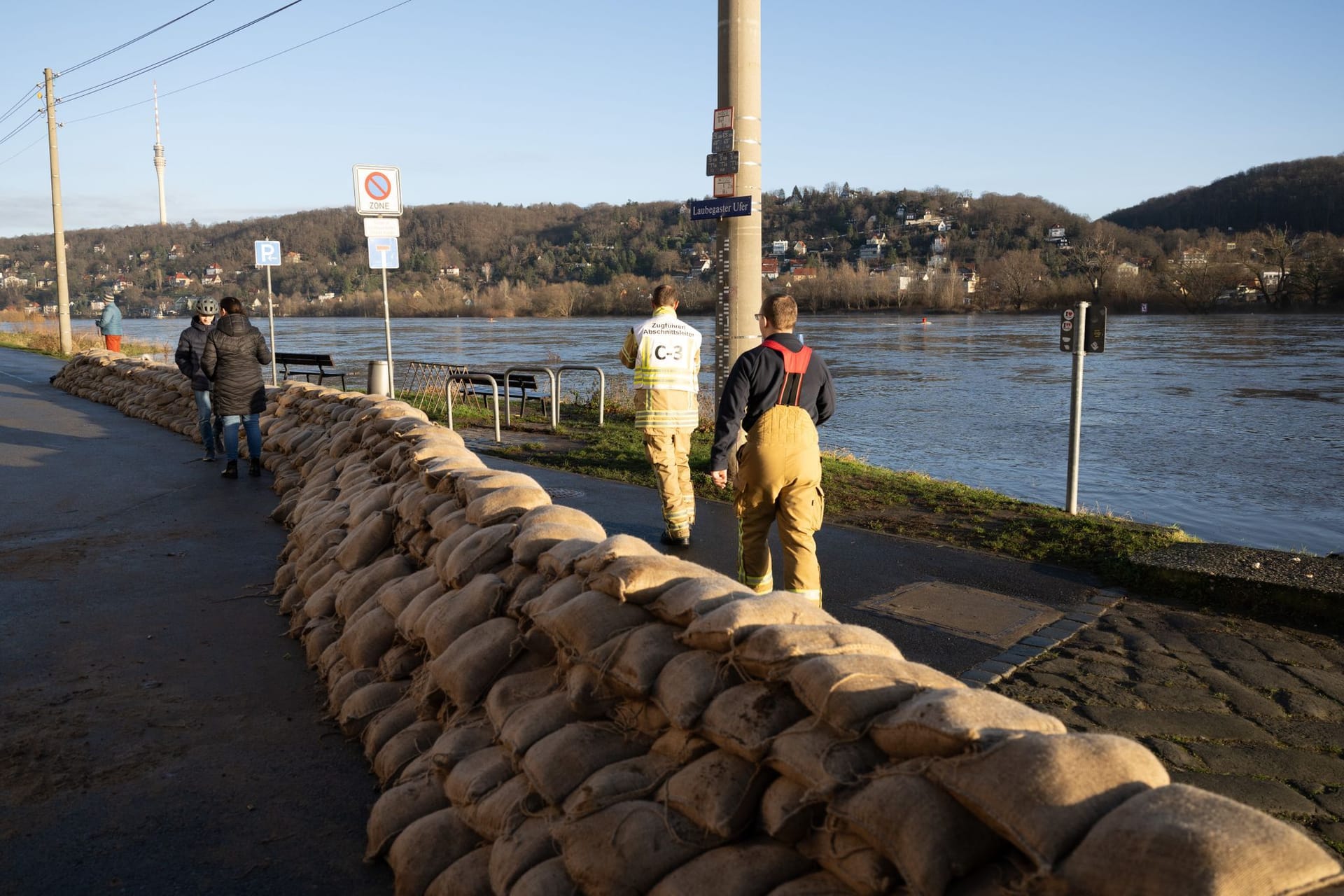 Feuerwehrmänner stehen im Dresdner Stadtteil Laubegast hinter einem Wall aus Sandsäcken am Ufer der Elbe. Das Hochwasser der Elbe in Dresden nähert sich weiter der zweithöchsten Alarmstufe drei.