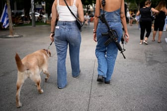 Eine Frau geht mit einem umgehängten Gewehr in Tel Aviv spazieren (Archivbild). Immer mehr Bürger fragen nach einem Waffenschein.