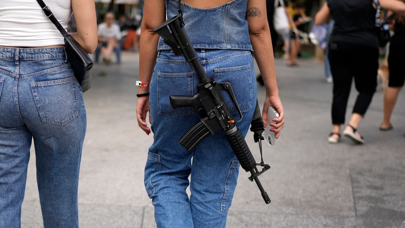 Eine Frau geht mit einem umgehängten Gewehr in Tel Aviv spazieren (Archivbild). Immer mehr Bürger fragen nach einem Waffenschein.