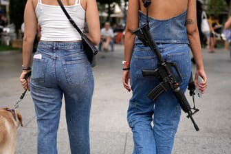 Eine Frau geht mit einem umgehängten Gewehr in Tel Aviv spazieren (Archivbild). Immer mehr Bürger fragen nach einem Waffenschein.