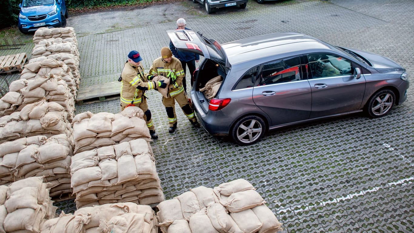 Einsatzkräfte der Feuerwehr geben auf einem Parkplatz in Oldenburg zahlreiche Sandsäcke an die Anwohner im Bereich der Hunte am Achterdiek aus.