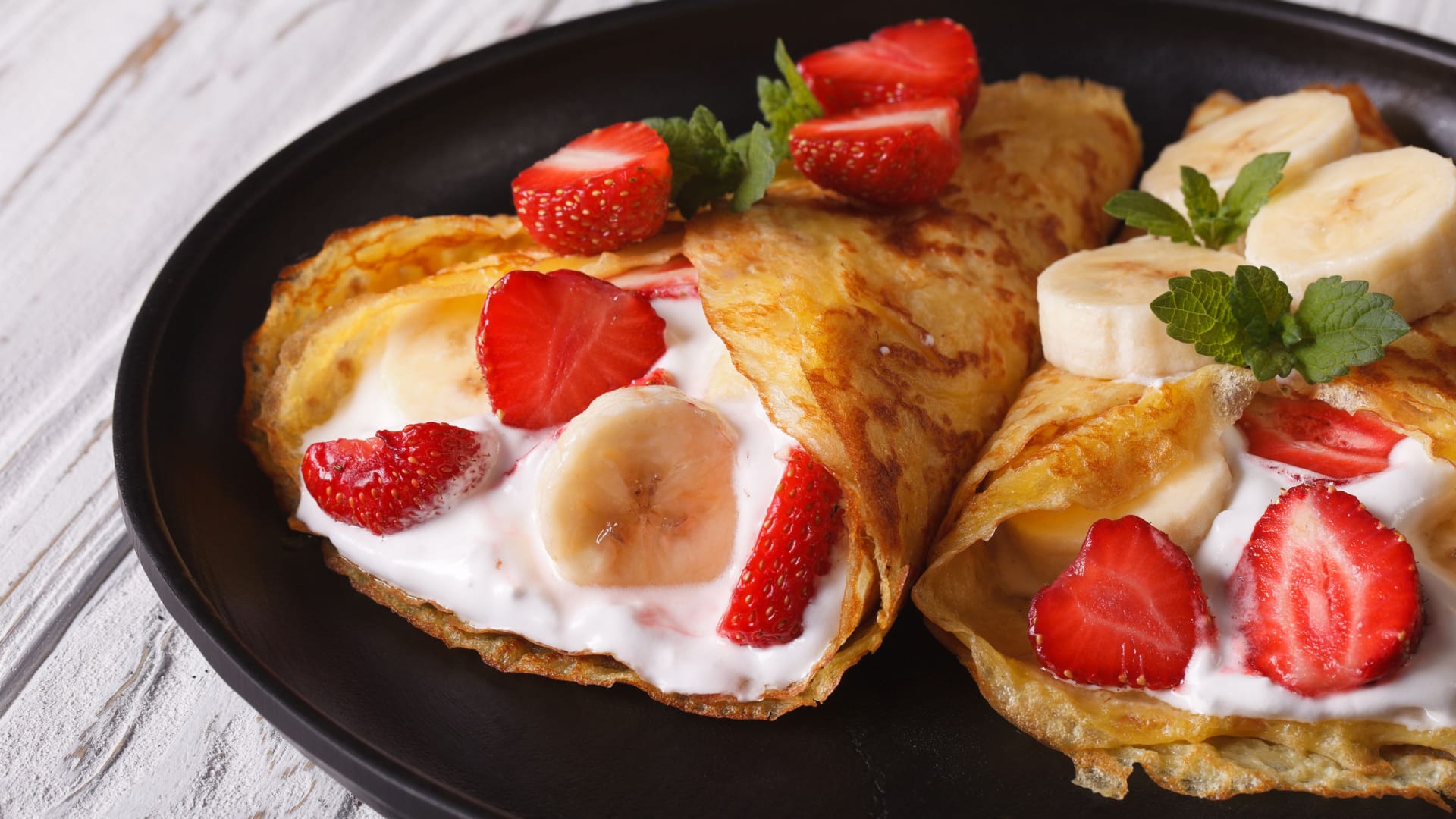 Gerollte Pfannkuchen mit einer Füllung aus Obst und Creme.