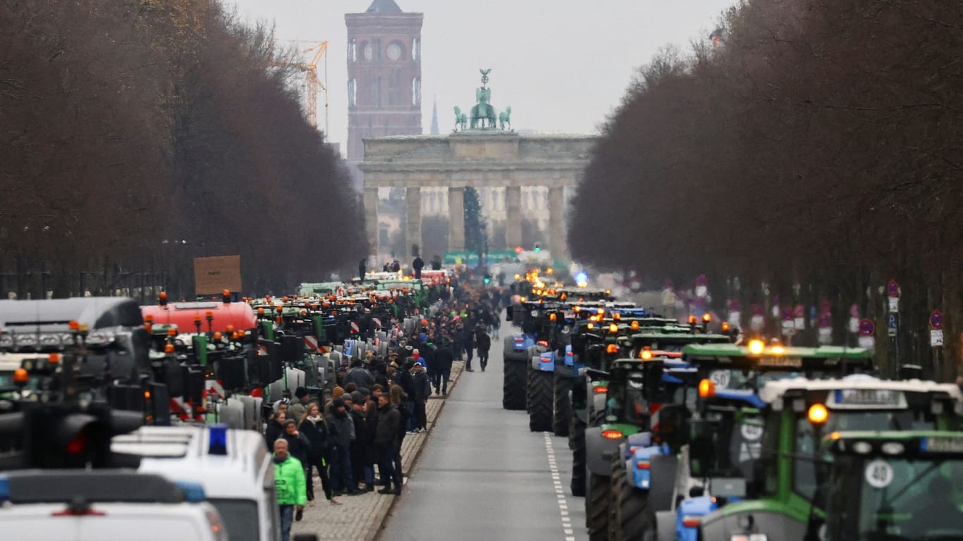 People stand beside tractors, as German farmers take part in a protest against the cut of vehicle tax subsidies, by the Brandenburg Gate, in Berlin, December 18, 2023