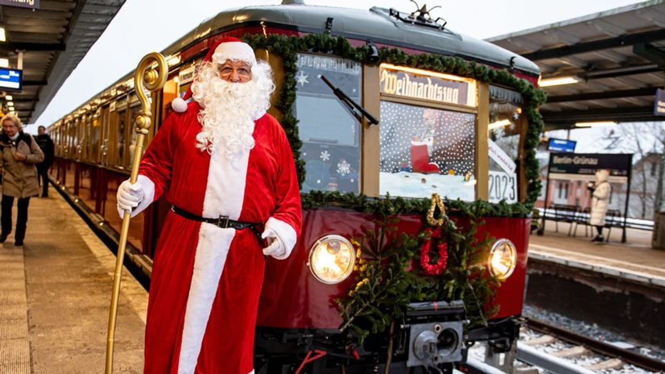 02.12.2023, Berlin: Ein Mann in Weihnachtsmannkostüm steht vor dem Weihnachtszug des Vereins Historische S-Bahn