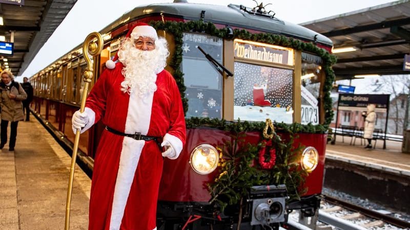 02.12.2023, Berlin: Ein Mann in Weihnachtsmannkostüm steht vor dem Weihnachtszug des Vereins Historische S-Bahn