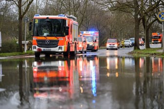 Hochwasser: Einsatzkräfte der Feuerwehr Hannover stehen bei einem Einsatz auf einer überfluteten Straße.