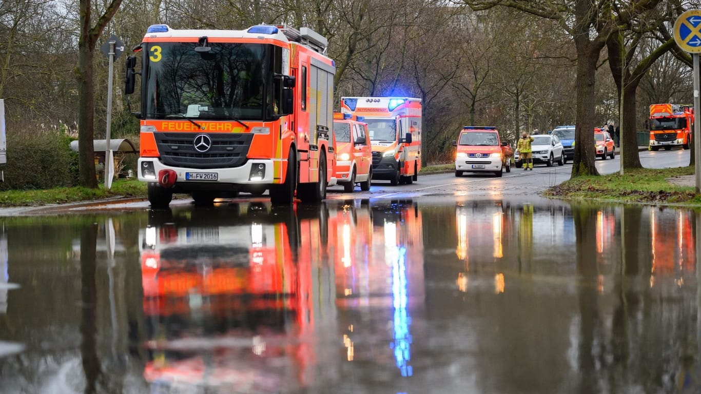 Hochwasser: Einsatzkräfte der Feuerwehr Hannover stehen bei einem Einsatz auf einer überfluteten Straße.