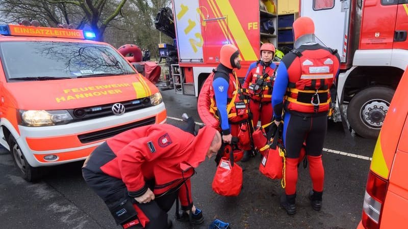 Einsatzkräfte der Wasserrettung der Feuerwehr stehen bei einem Einsatz auf einer überfluteten Straße: Der Mann wählte den Notruf.