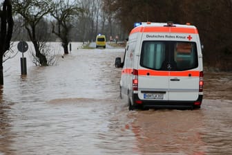 Windehausen: Ein Krankenwagen fährt über eine von Hochwasser überflutete Straße in den Ort.