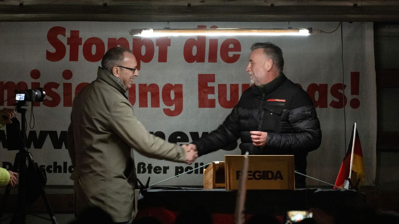 Jörg Urban (l), Vorsitzender der AfD Sachsen, wird auf einer Kundgebung der rechtsextremistischen Bewegung Pegida von dem Gründer der Bewegung, Lutz Bachmann, auf der Bühne begrüßt.