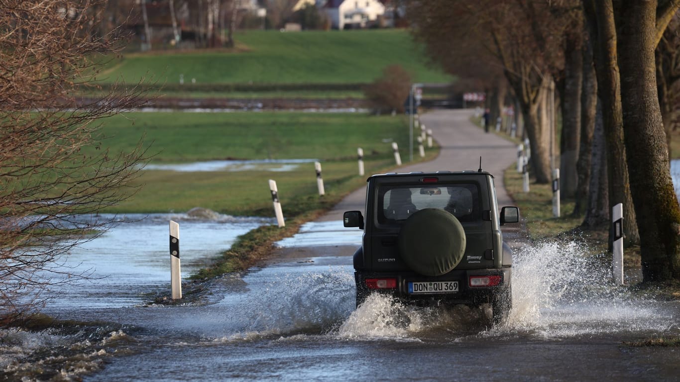 Bayern, Gessertshausen: Ein Auto fährt auf einer vom Hochwasser der Schmutter überfluteten Straße.