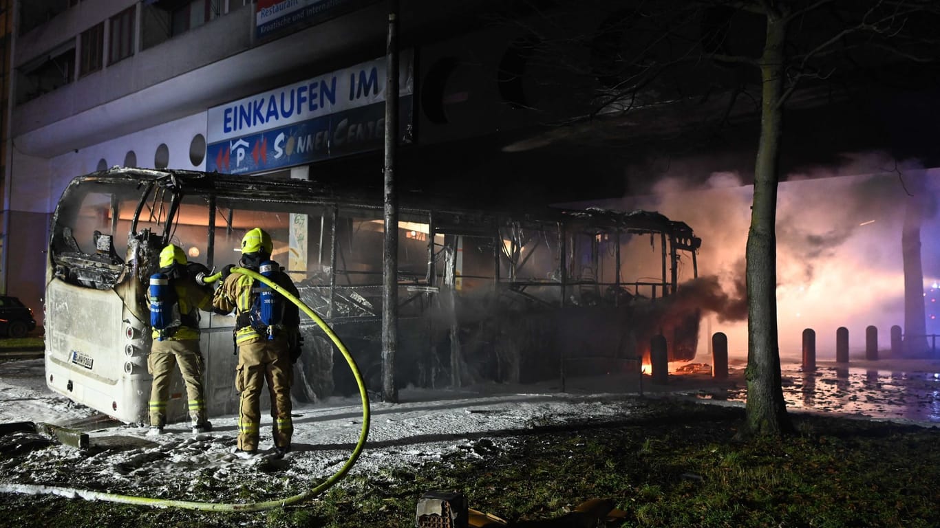 Feuerwehrleute löschen in der Silvesternacht im Bezirk Neukölln einen brennenden Bus.