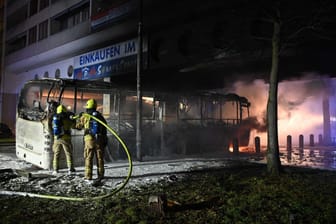 Feuerwehrleute löschen in der Silvesternacht im Bezirk Neukölln einen brennenden Bus.