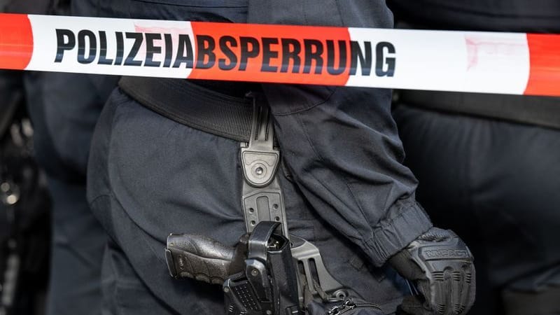 Polizisten stehen hinter einem Polizei-Flatterband (Symbolfoto): Bislang gebe es keine Hinweise auf den Täter, teilten die Beamten mit. Polizisten stehen hinter einem Polizei-Flatterband (Symbolfoto): Bislang gebe es keine Hinweise auf den Täter, teilten die Beamten mit.