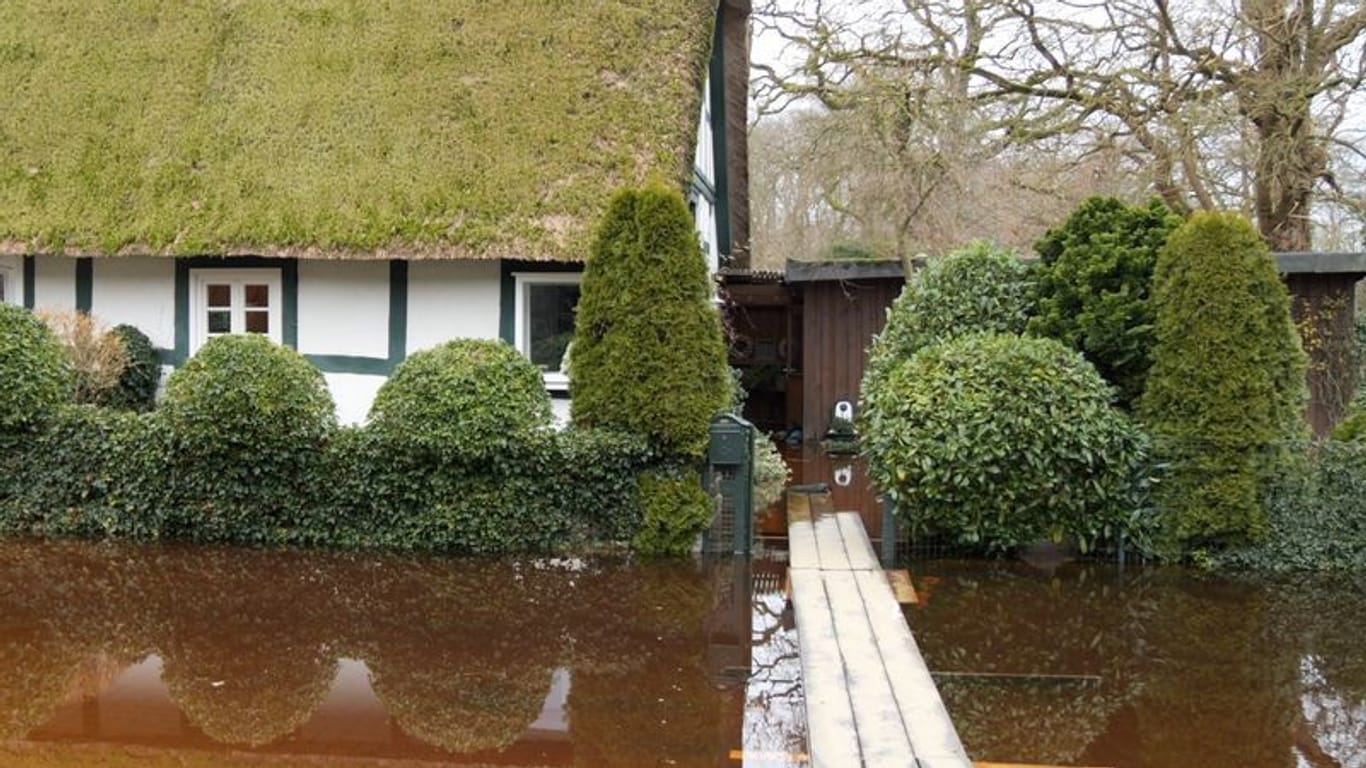 Bretter liegen zum Überqueren von Hochwasser vor einem Haus. Rund um Bremen bleibt die Lage angespannt.