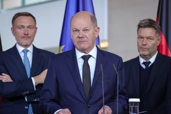 Bundeskanzler Olaf Scholz steht an einem Podium. Hinter ihm stehen Wirtschaftsminister Robert Habeck und Finanzminister Christian Lindner.