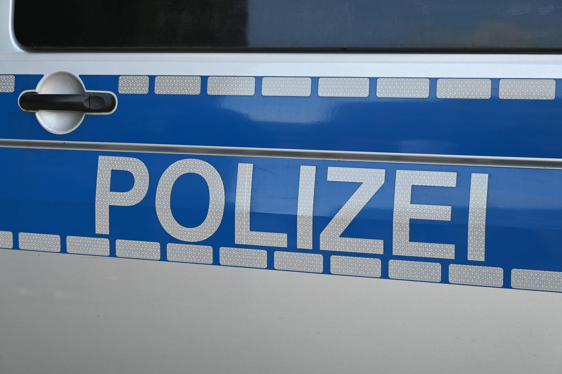 Schriftzug Polizei an einem Polizeiwagen (Symbolfoto): Nach einem Messerangriff auf einen Rollstuhlfahrer ermittelt die Polizei gegen einen Frau wegen versuchten Mordes.