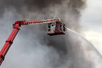 Löscharbeiten der Feuerwehr vor einer großen Rauchwolke (Symbolbild): In Nordfriesland läuft ein Großeinsatz.