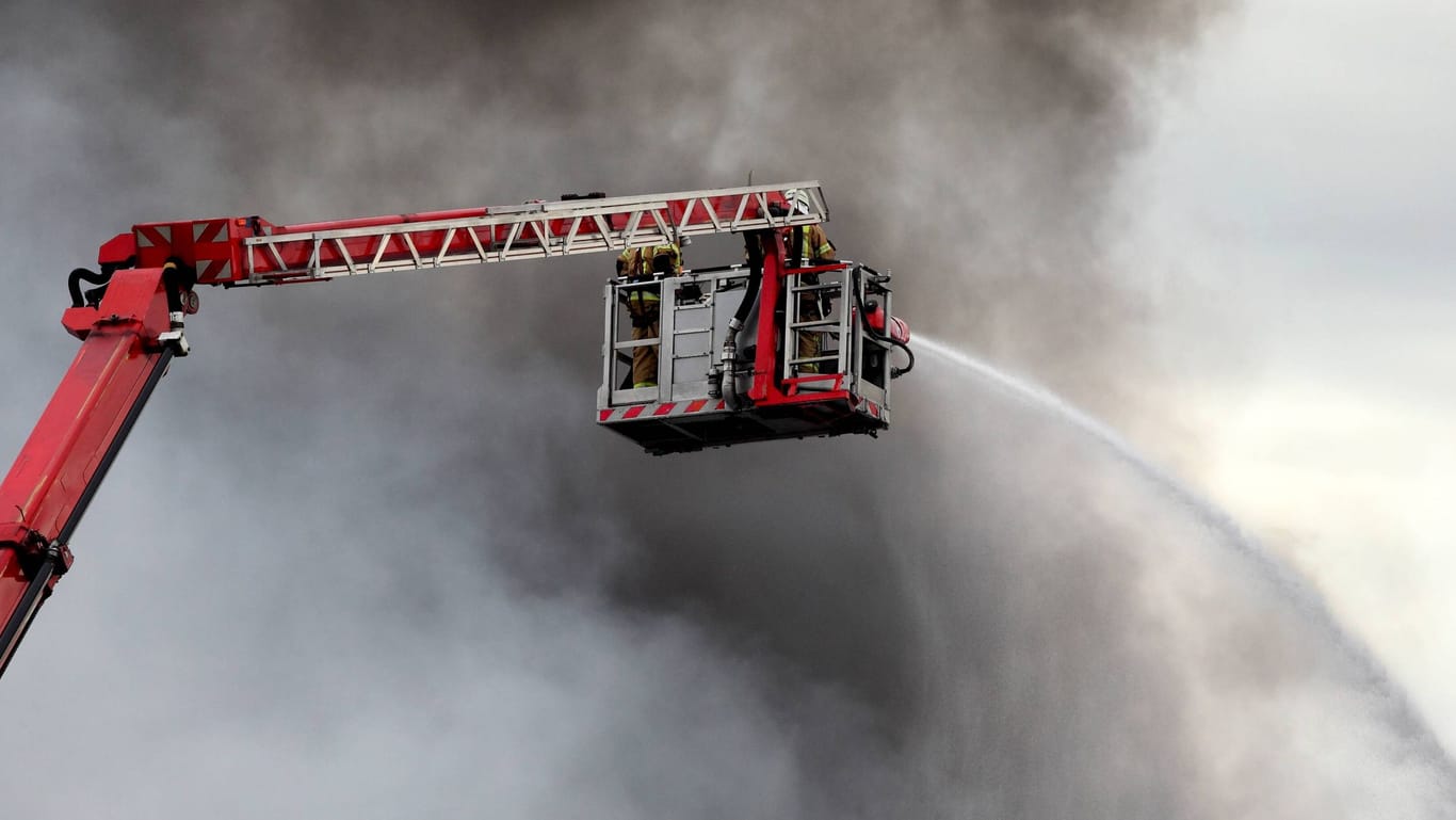 Löscharbeiten der Feuerwehr vor einer großen Rauchwolke (Symbolbild): In Nordfriesland läuft ein Großeinsatz.