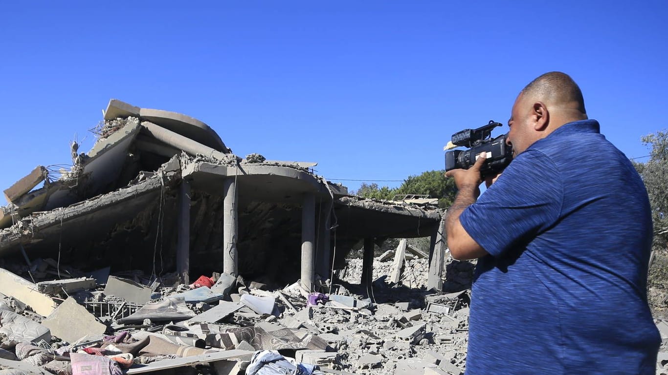 Ein Mann filmt ein Gebäude, dass von israelischen Helikoptern zerstört worden ist: Der gegenseitige Beschuss an der Grenze zwischen Libanon und Israel setzt sich fort.