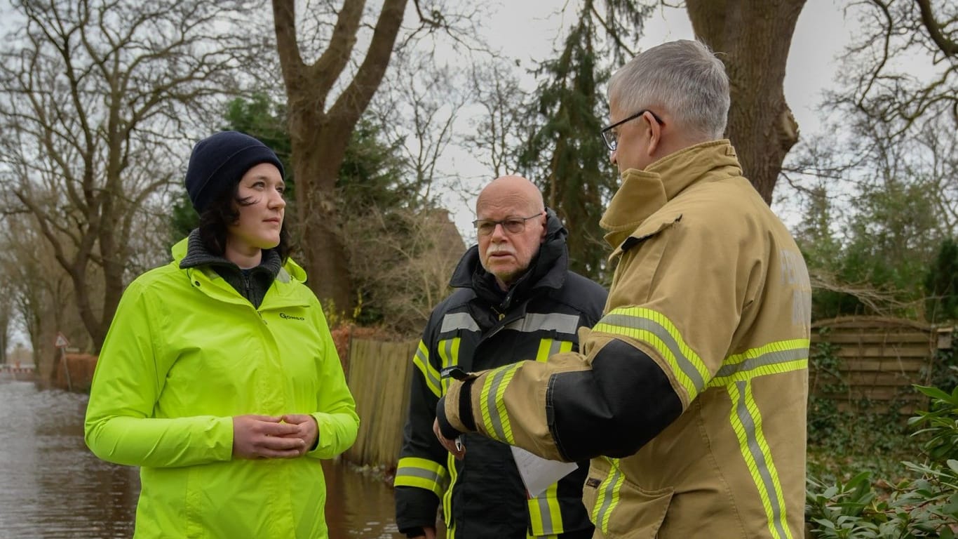 Umweltsenatorin Kathrin Moosdorf (links) und Innensenator Ulrich Mäurer (Mitte) lassen sich in Bremen-Borgfeld die aktuelle Hochwasserlage vom stellvertretenden Leiter der Feuerwehr Bremen, Michael Richartz, erläutern.