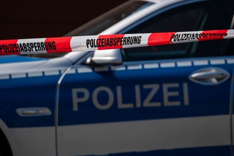 Ein Polizeiauto steht hinter einem Absperrband der Polizei