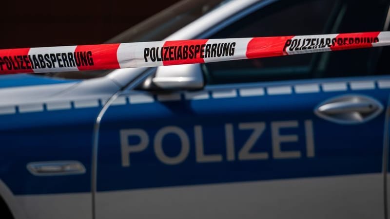 Ein Polizeiauto steht hinter einem Absperrband der Polizei