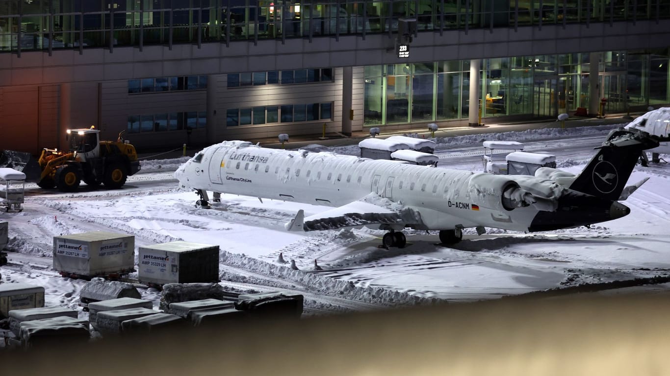 Eine Lufthansa Maschine am verschneiten Münchner Flughafen: Auch am Dienstag wird der Flugbetrieb teilweise eingestellt.