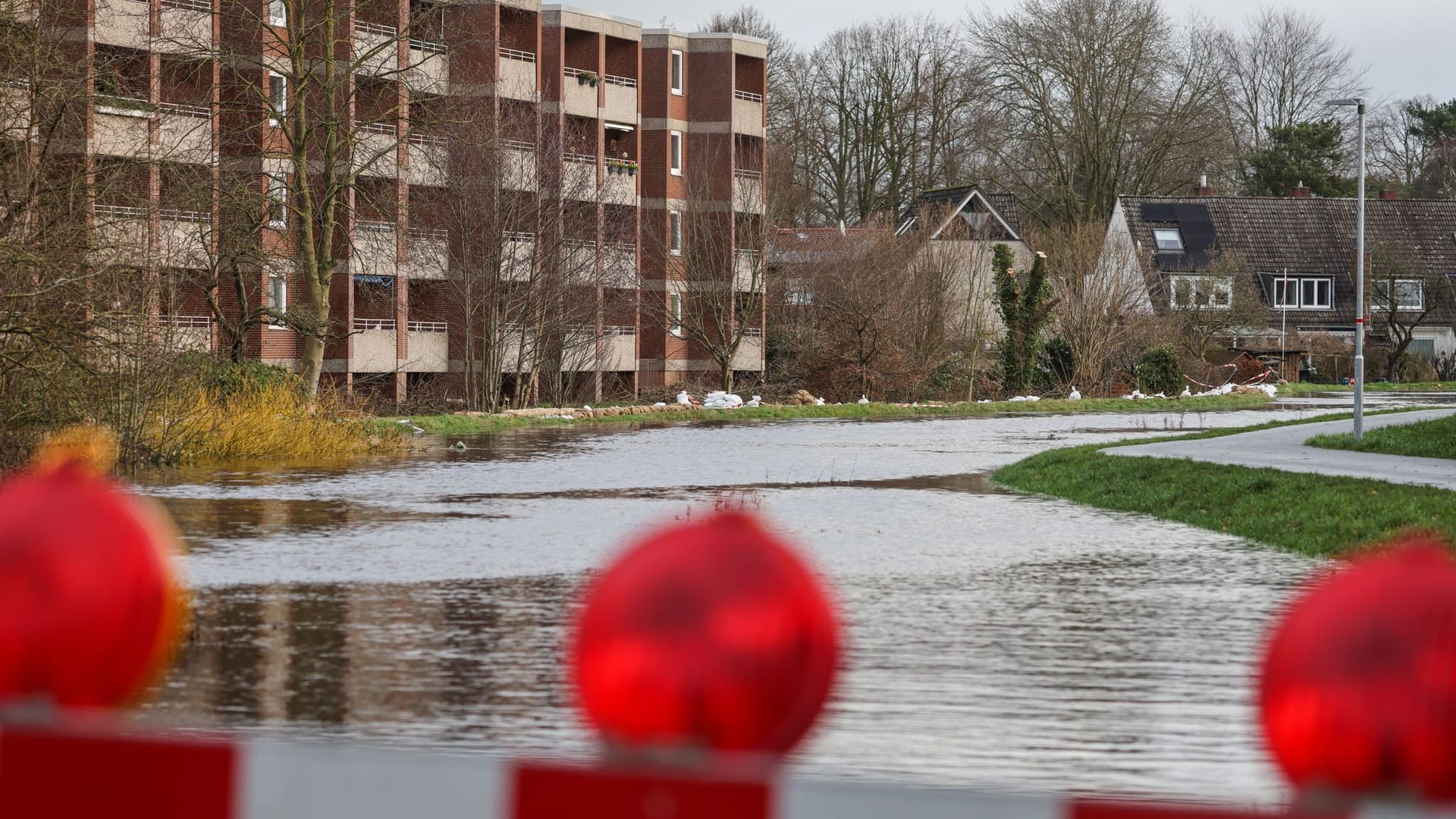 Sandsäcke liegen auf einem durchweichten Deich vor evakuierten Wohnhäusern an der Wörpe in Lilienthal. Ein Deichriss in der Nähe hält die Einsatzkräfte weiter in Atem.