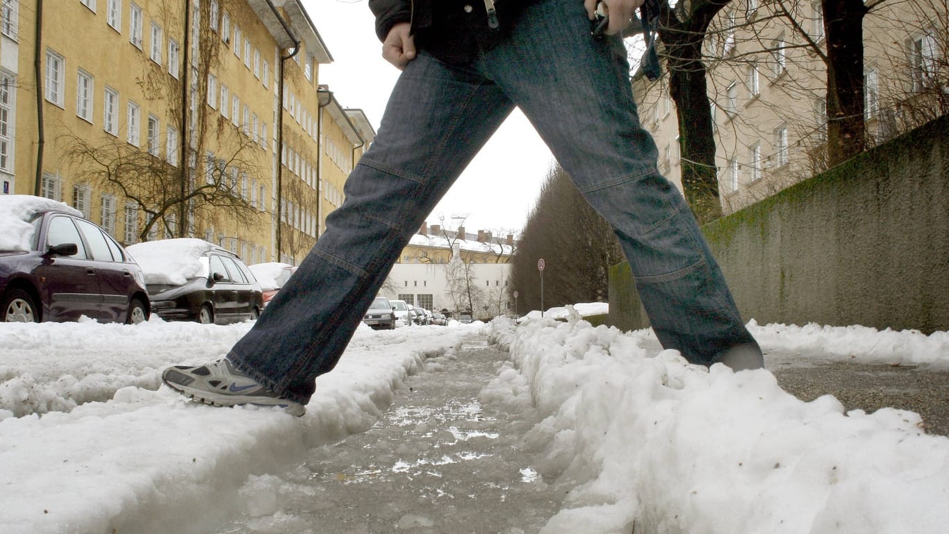 Fußgänger steht im Schneematsch (Symbolbild) - hält der Winter Einzug in der Stadt?