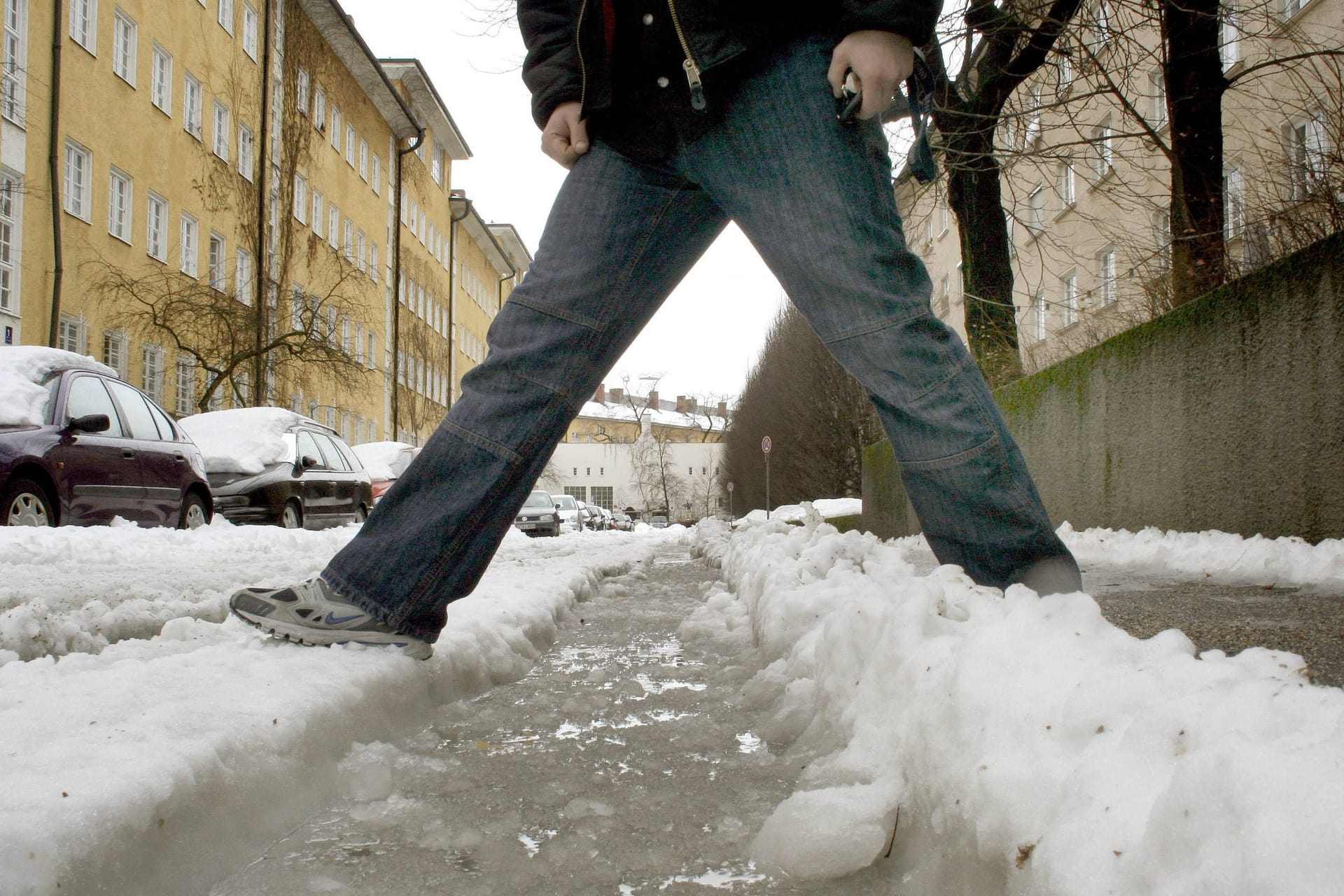 Fußgänger steht im Schneematsch (Symbolbild) - hält der Winter Einzug in der Stadt?