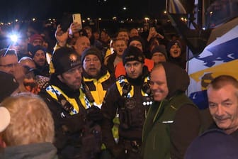 Polizisten diskutieren mit Landwirten auf einer Kreuzung mit Zufahrt zum Hafen im Süden von Hamburg. Die Bauernproteste hielten auch in der Nacht zum Dienstag an.