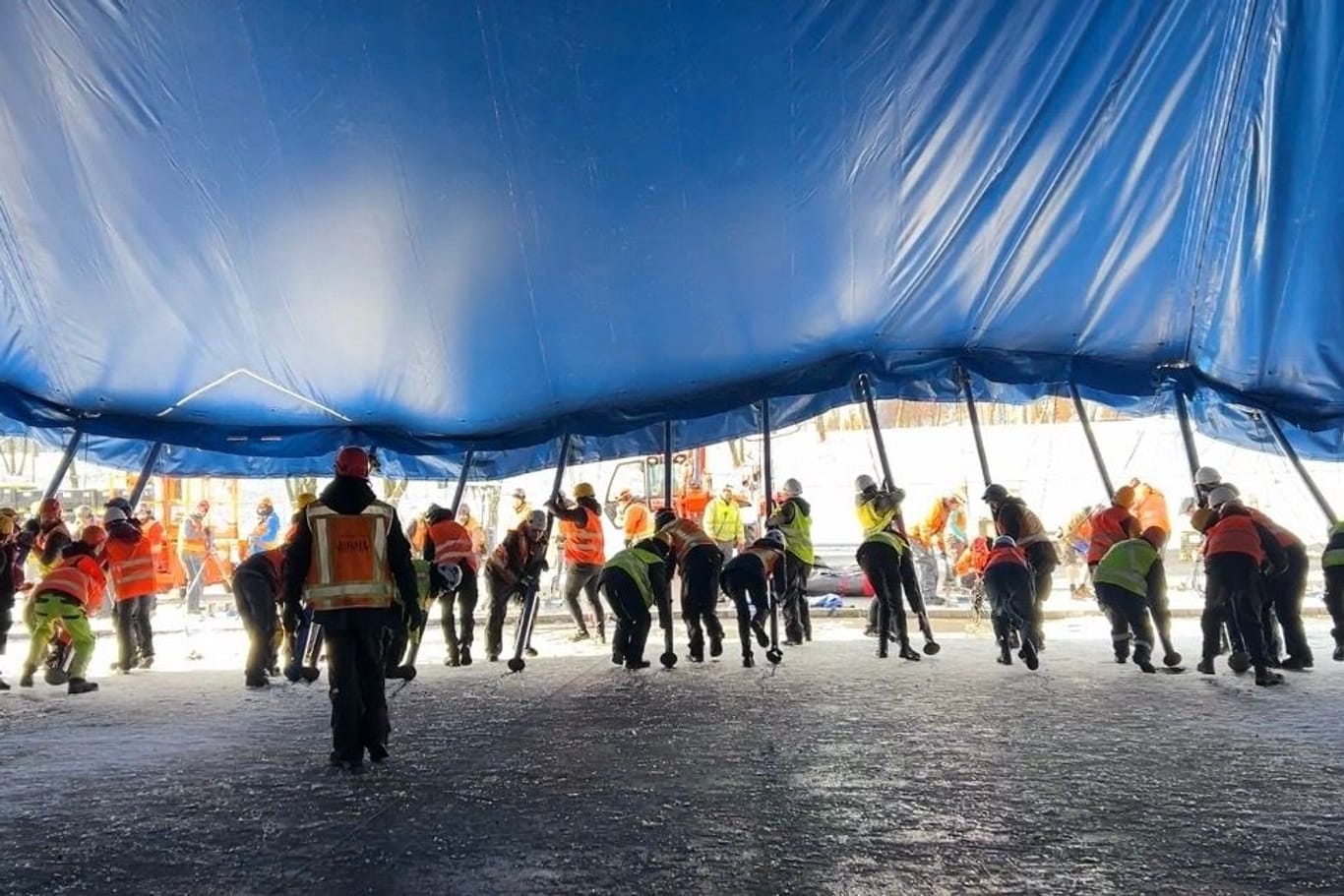 Arbeiter heben das Zelt auf die Pfeiler.
