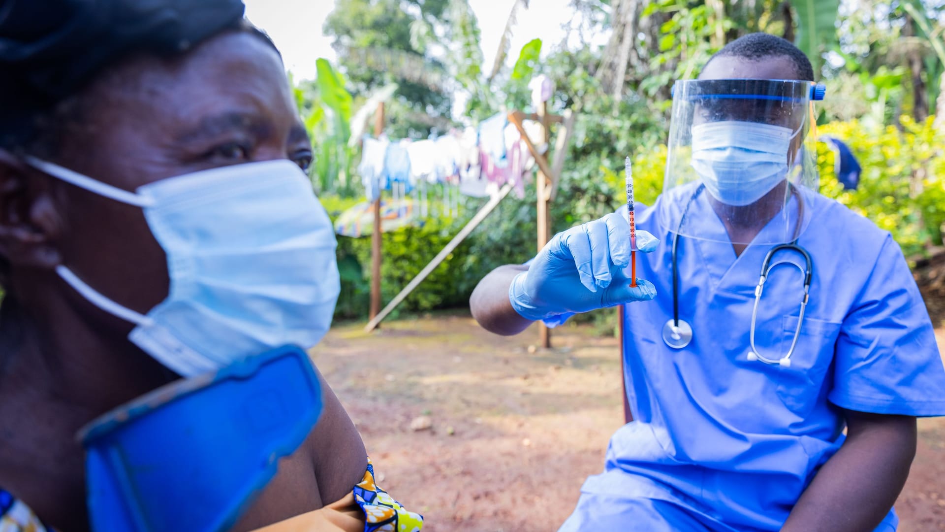 Elder African woman uncovers her shoulder and is ready to receive injection from a doctor