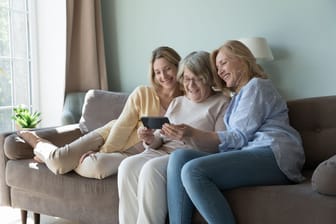 Mutter, Tochter und Enkeltochter sitzen auf dem Sofa