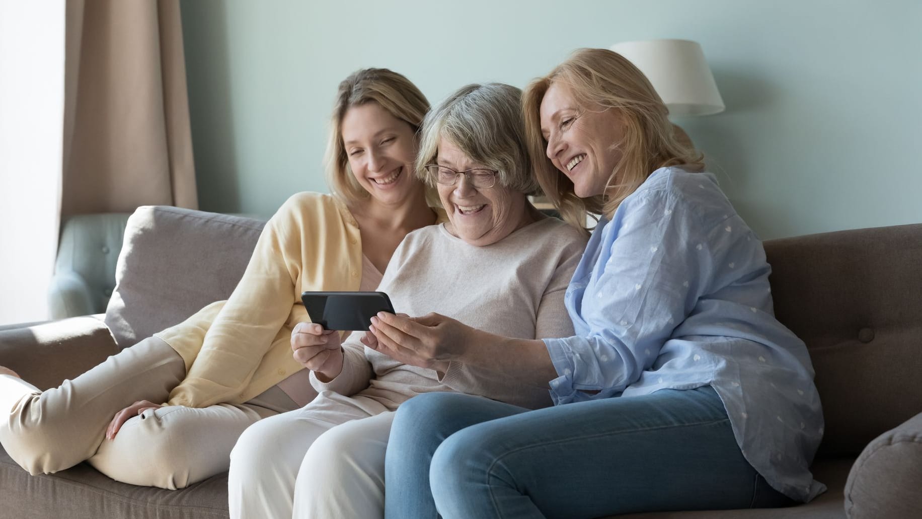 Mutter, Tochter und Enkeltochter sitzen auf dem Sofa