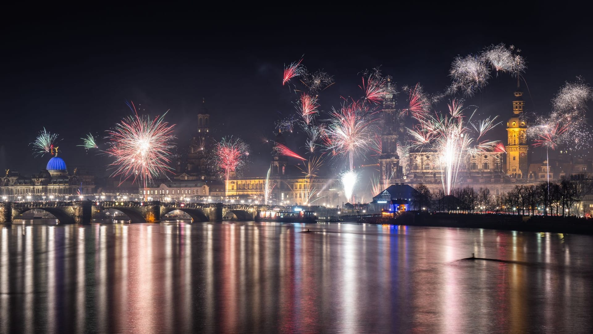 Feuerwerk explodiert in der Silvesternacht über der histoischen Altstadtkulisse an der Elbe: Zu sehen ist die Kuppel der Kunstakedmie mit dem Engel "Fama" (l-r), die Frauenkirche, das Ständehaus, die Hofkirche und der Hausmannsturm.