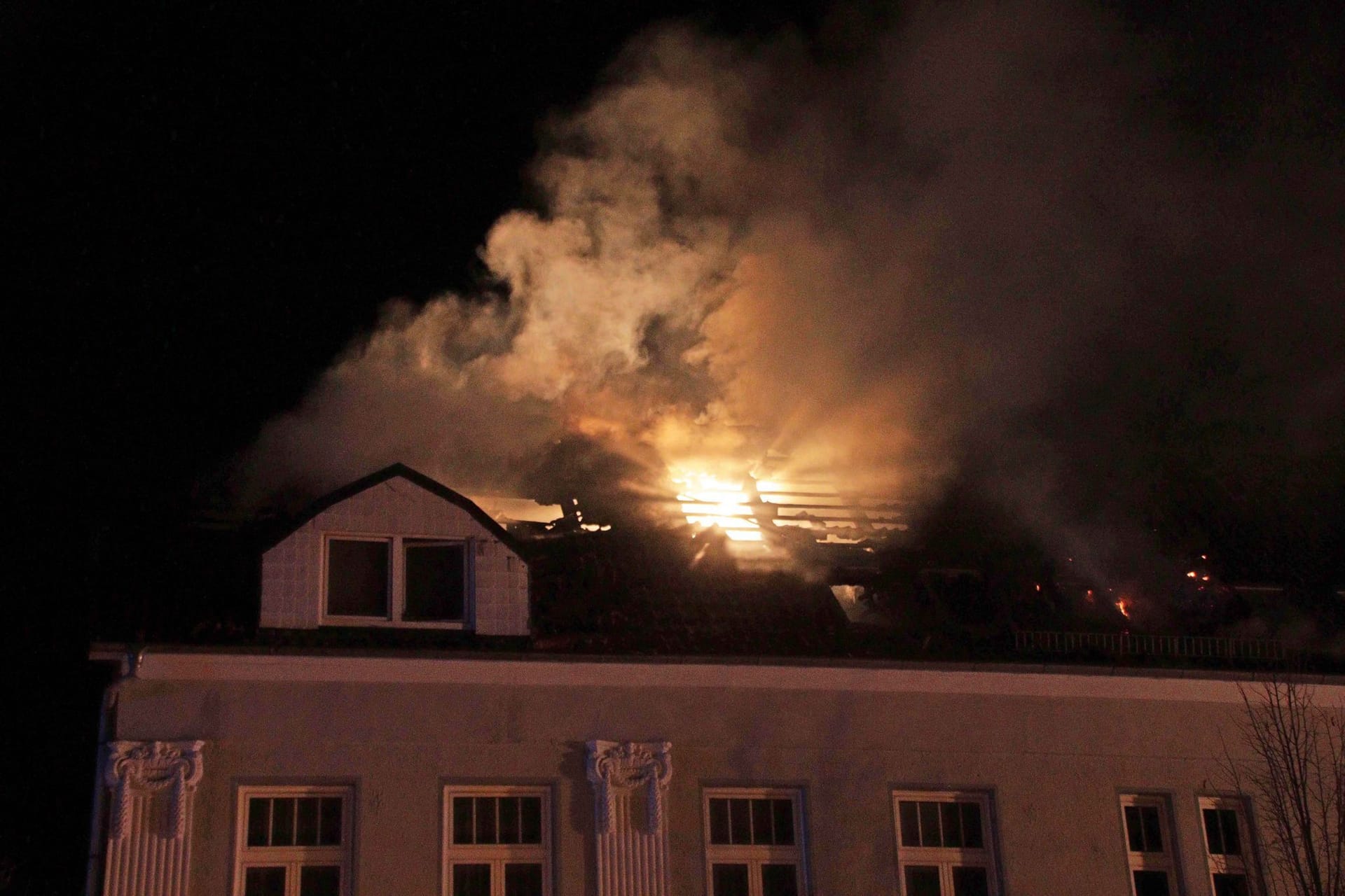 Rauch und Flammen sind bei einem Brand in einem Mehrfamilienhaus über dem Dach zu sehen. Bei dem Brand in Ludwigslust sind mehrere Mitglieder einer Familie verletzt worden, darunter ein Dreijähriger schwer.