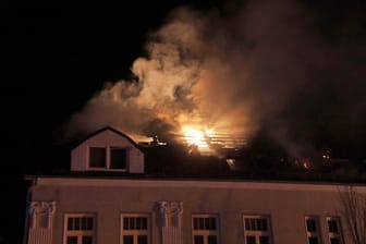Rauch und Flammen sind bei einem Brand in einem Mehrfamilienhaus über dem Dach zu sehen. Bei dem Brand in Ludwigslust sind mehrere Mitglieder einer Familie verletzt worden, darunter ein Dreijähriger schwer.