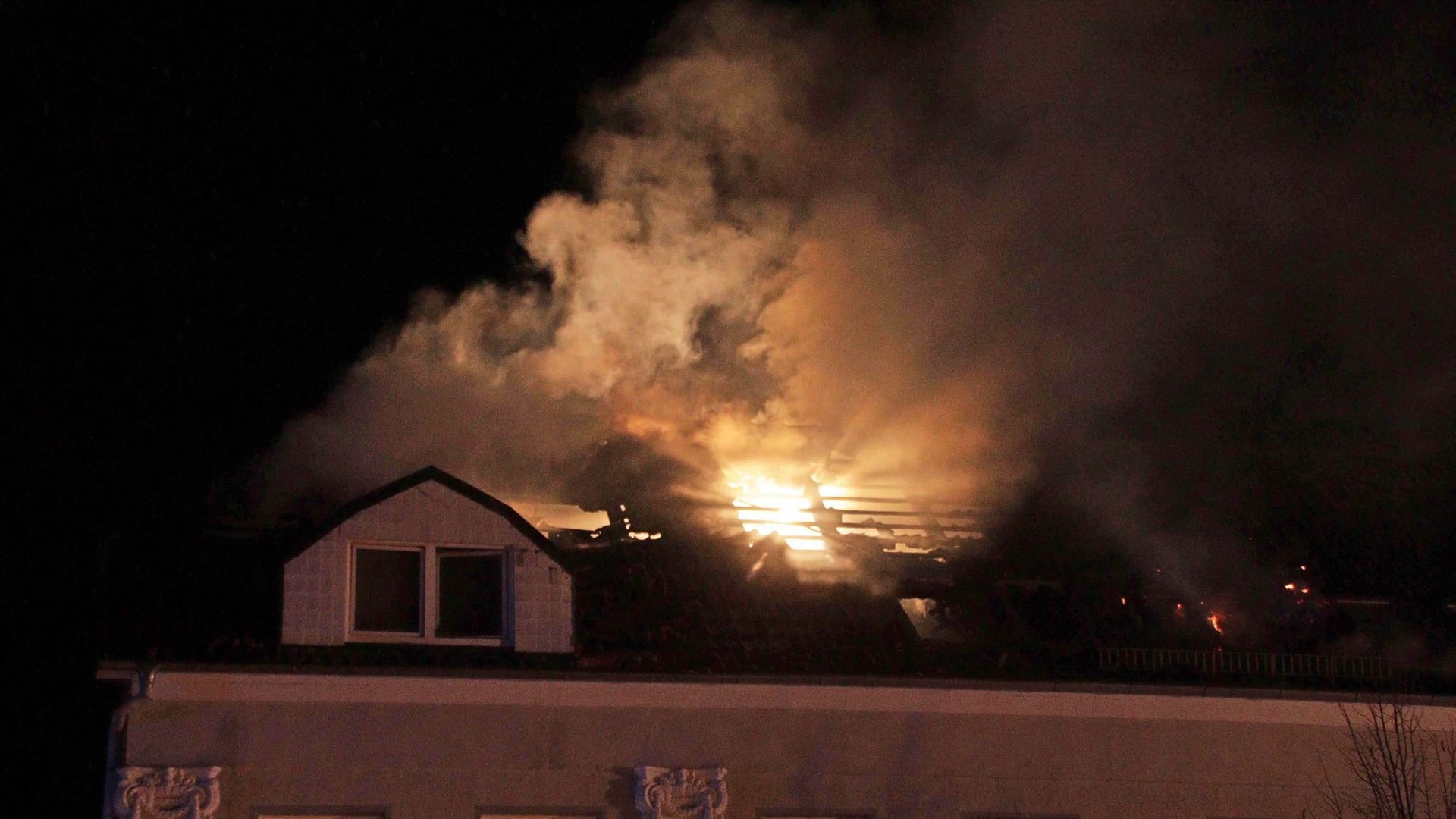 Rauch und Flammen sind bei einem Brand in einem Mehrfamilienhaus über dem Dach zu sehen. Bei dem Brand in Ludwigslust sind mehrere Mitglieder einer Familie verletzt worden, darunter ein Dreijähriger schwer.